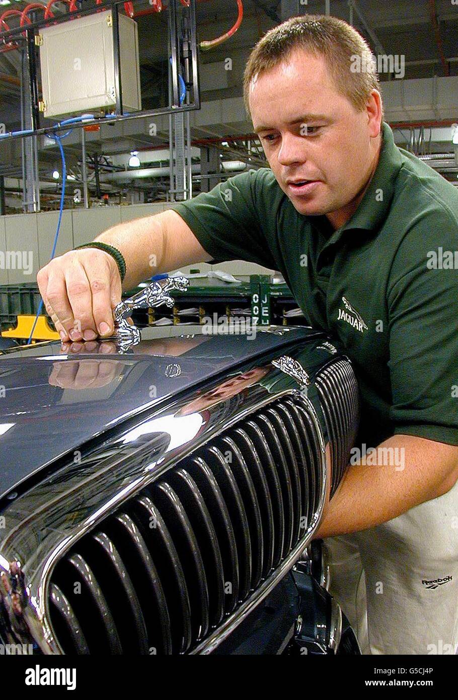 Jamie Lovett fixes the famous leaping Jaguar on top of the bonnet of the new Jaguar X-Type, at a photocall to mark the official opening of the Halewood Manufacturing Plant in Liverpool, the home of the new Jaguar. Stock Photo