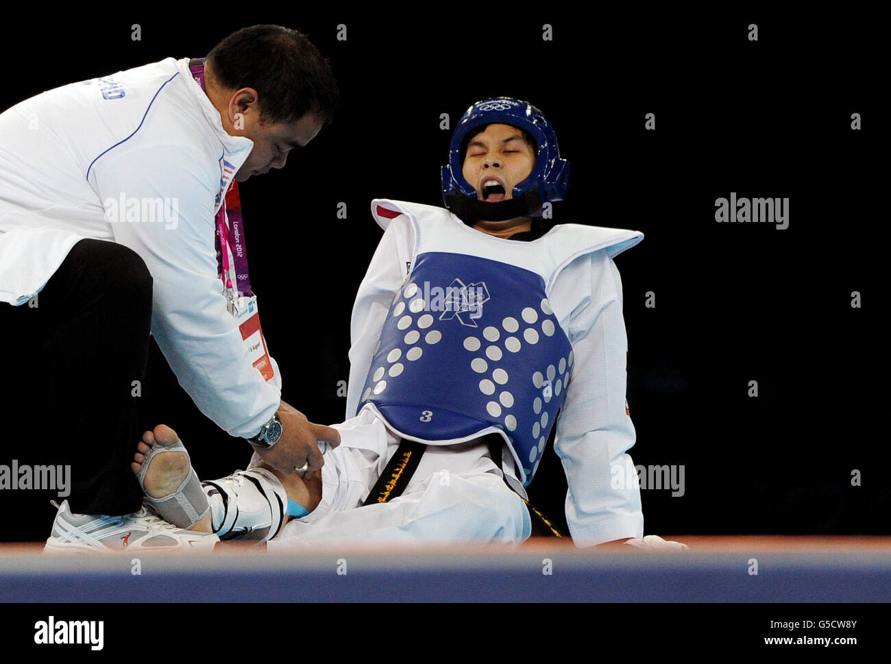 Thailand's Pen-Ek Karaket (blue) reacts as he competes against Korea's Daehoon Lee during the Men's (-58kg) Taekwondo at the ExCel centre, London Stock Photo