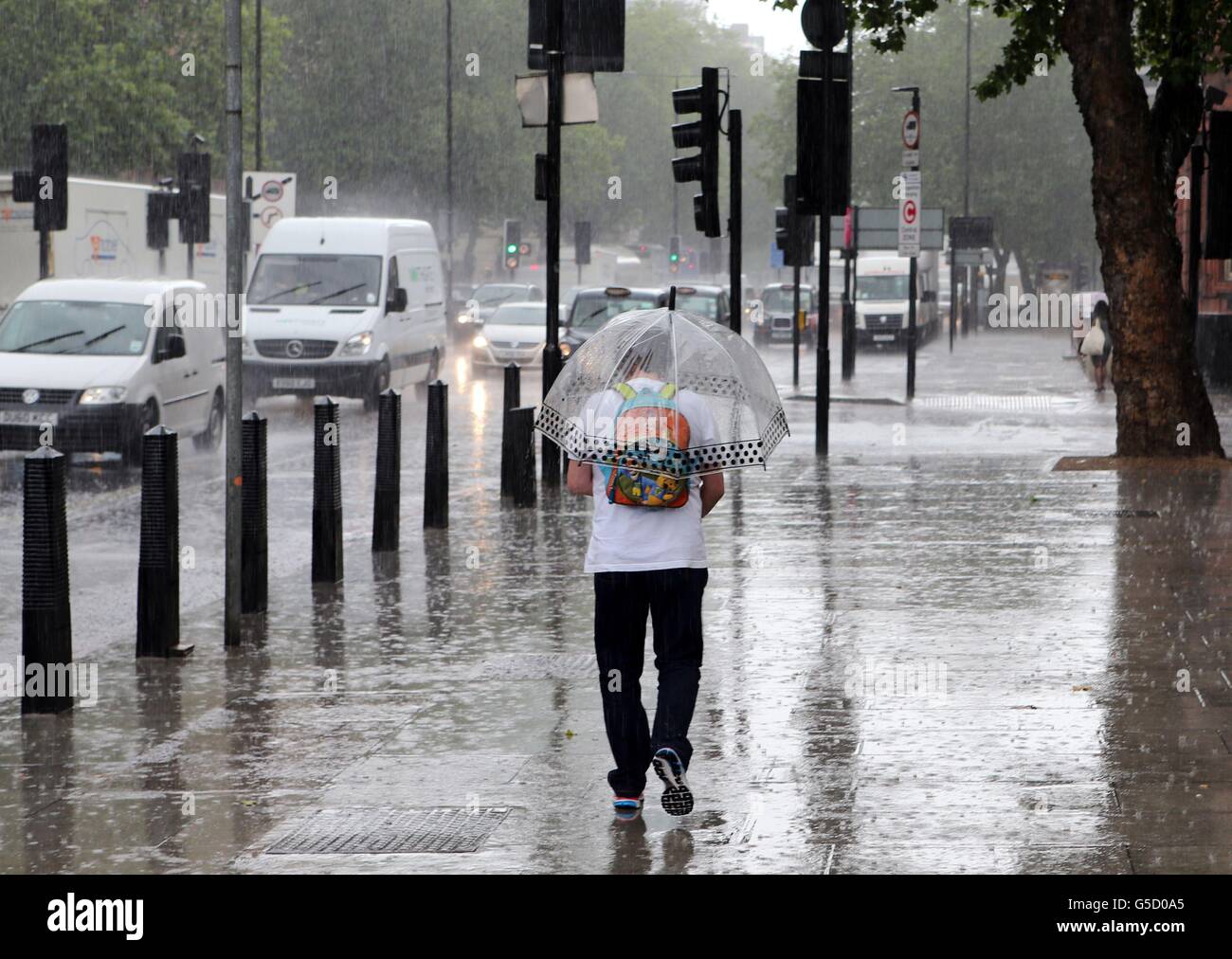 Members of the public make their way through a heavy rain shower in