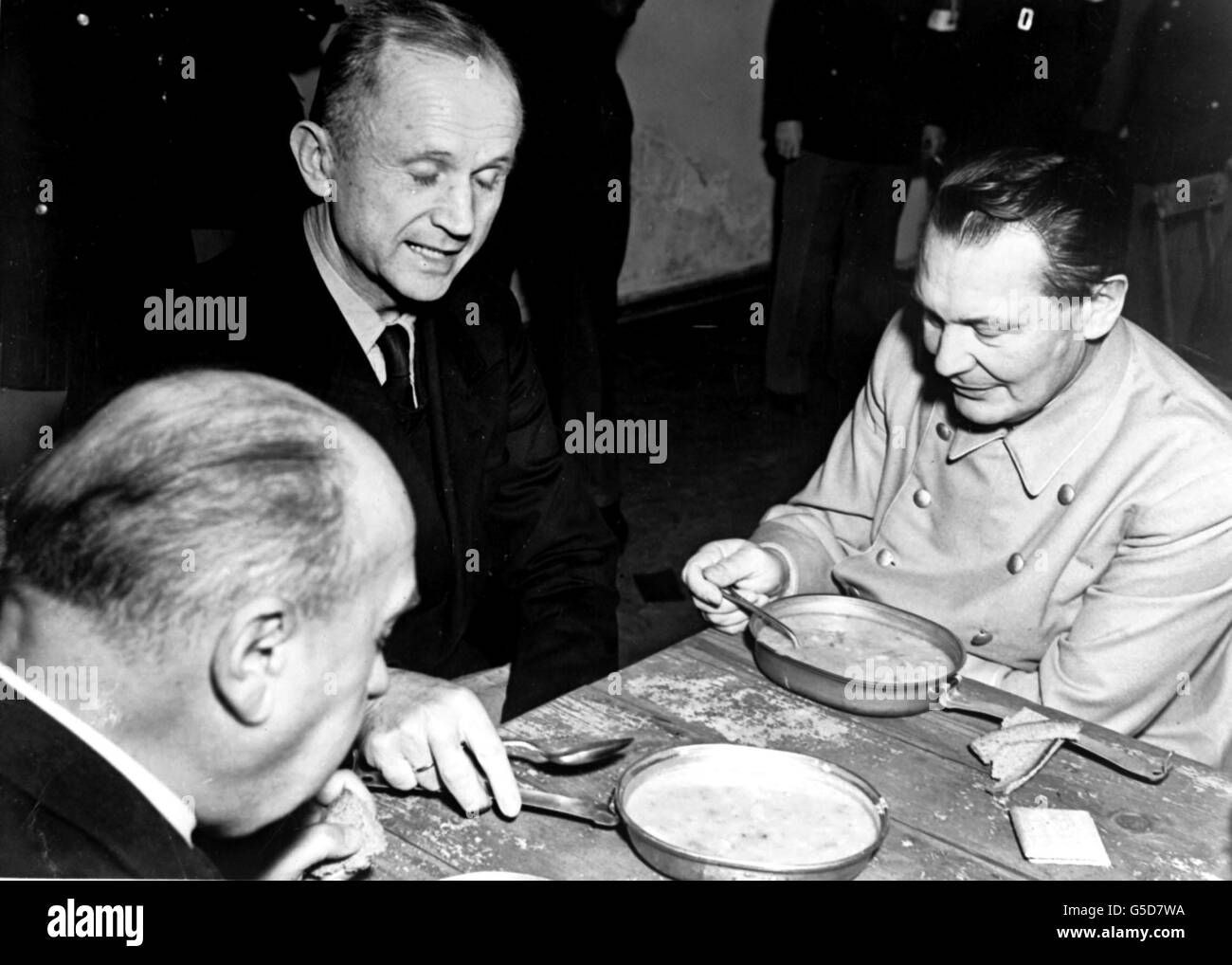 Admiral Karl Doenitz (c), Fuhrer of the German Reich after Hitler's suicide, eats with former Reichsmarschall Hermann Goering (r), under guard during the post-war Nuremberg Trials. The trials at the Palace of Justice began on the 20th November 1945. Picture part of PA Second World War collection. Stock Photo