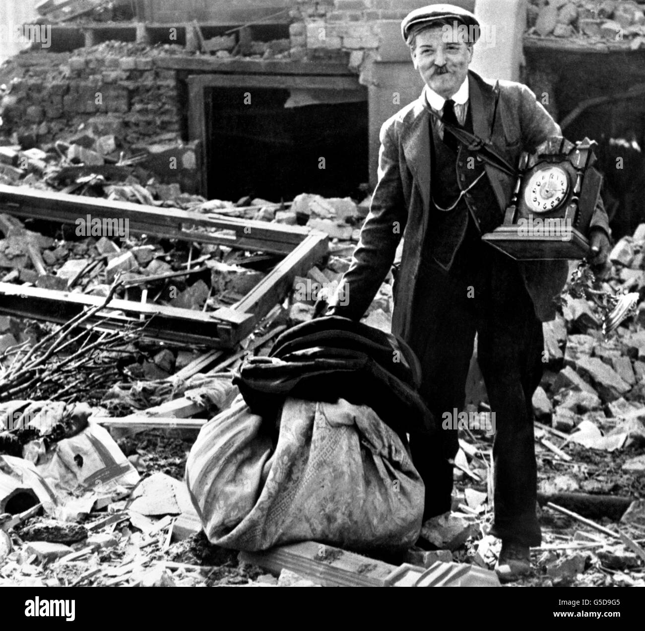 A Londoner, still smiling, while recovering the remains of his belongings from the rubble of his bomb-damaged home. Stock Photo