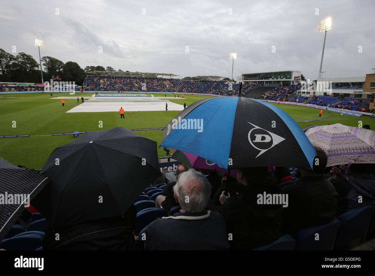 Fans with umbrella's as start is delayed due to rain during the first One Day International match at the SWALEC Stadium, Cardiff. Stock Photo