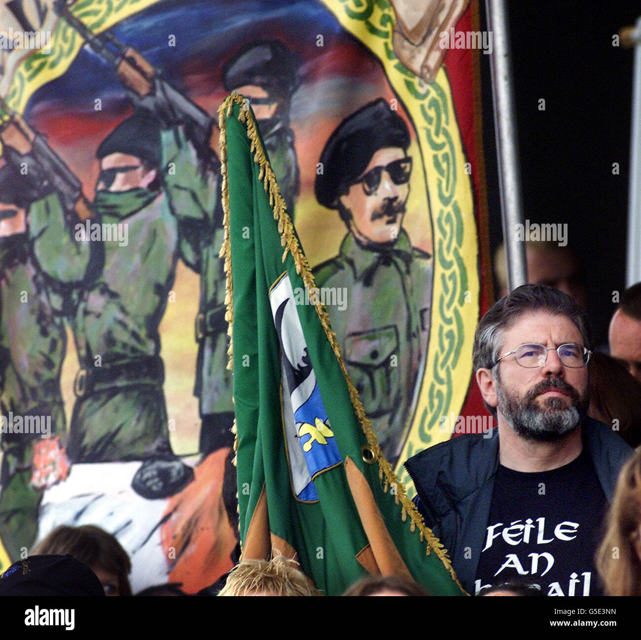 Sinn Fein President Gerry Adams beside a banner depicting IRA men firing a volley of shots over the coffin of a Hunger Striker. Adams, was attending a Republican rally in west Belfast, to commerate the 20th anniversary of the hunger strikes in the H-blocks. *Speaking at the rally, Mr Adams annouced he will not allow the Government to resolve outstanding issues in the peace process on its own or unionist terms. Stock Photo