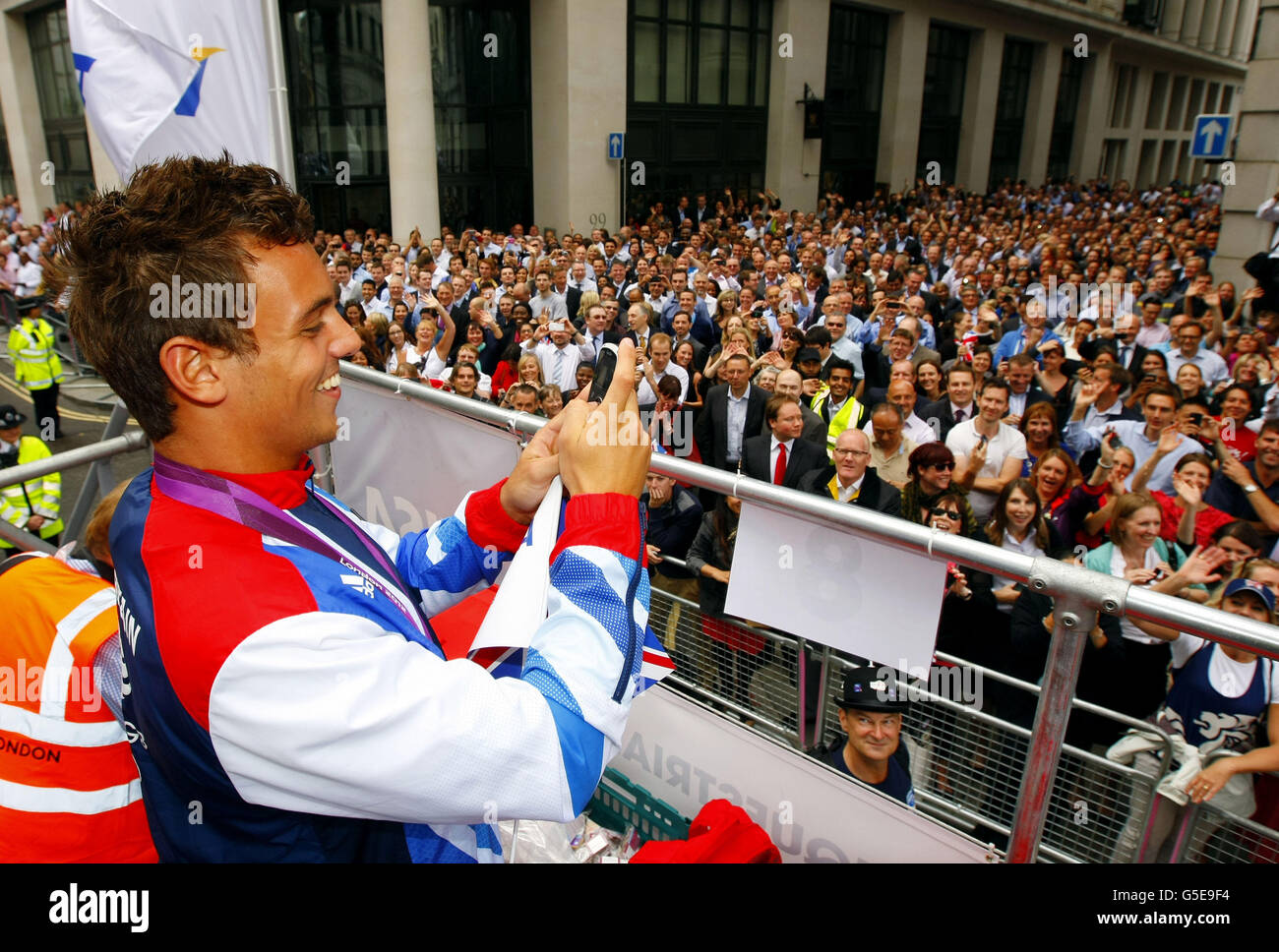 Diver Tom Daley films the crowd with his phone as he takes part in a parade through London, celebrating Britain's Olympic and Paralympic sporting heroes. Stock Photo