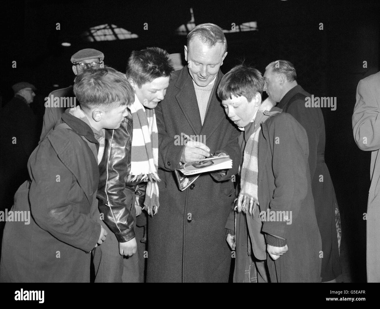 Liverpool boys visiting London to see Everton's fourth round FA Cup tie with Charlton meet Tooting and Mitcham players leaving from St.Pancras Station for their third round match with Nottingham Forest. Centre forward Paddy Hasty obliges with autographs for (from left) James Hogg, (12); Brian Dunleavy (15); and Charles McGaw. (14). Stock Photo