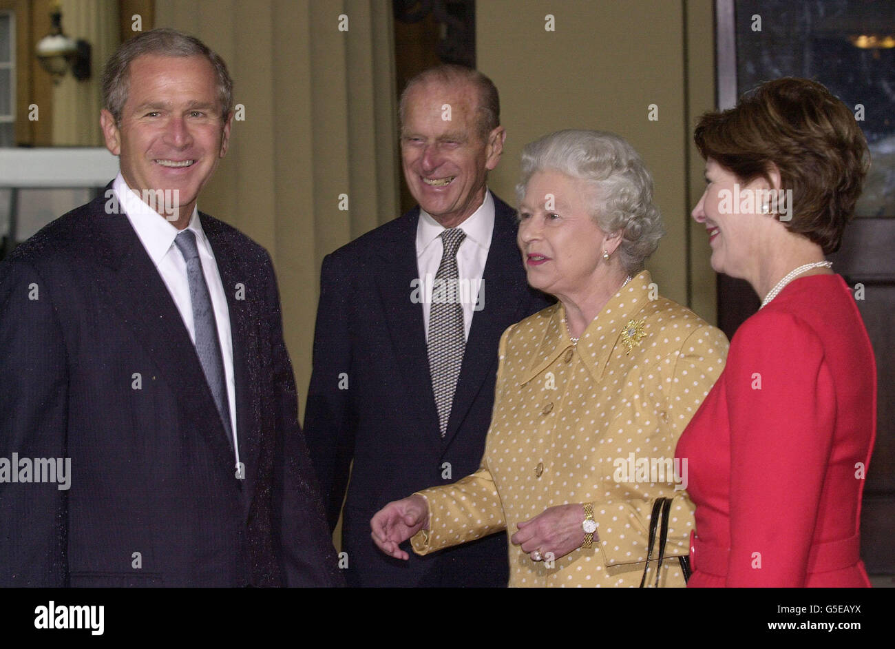 America's President Bush (left) stands, his jacket covered with rain, alongside Britain's Queen Elizabeth II and the Duke of Edinbugh as he arrives with his wife, Laura, at Buckingham Palace for lunch. The US president is on his first visit to the United Kingdom, before travelling on to the G8. Stock Photo