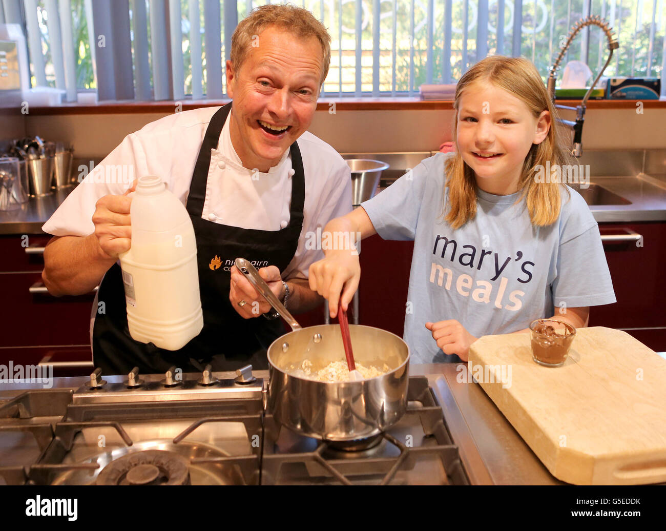 TV chef Nick Nairn cooks nine-year old blogger Martha Payne some porridge at his cookery school prior to her travelling to Malawi, next month Martha will travel to Malawi where she will see meet some of the children who receive a daily meal from Mary's Meals, for a whole school year, thanks to support from Martha's blog. Stock Photo