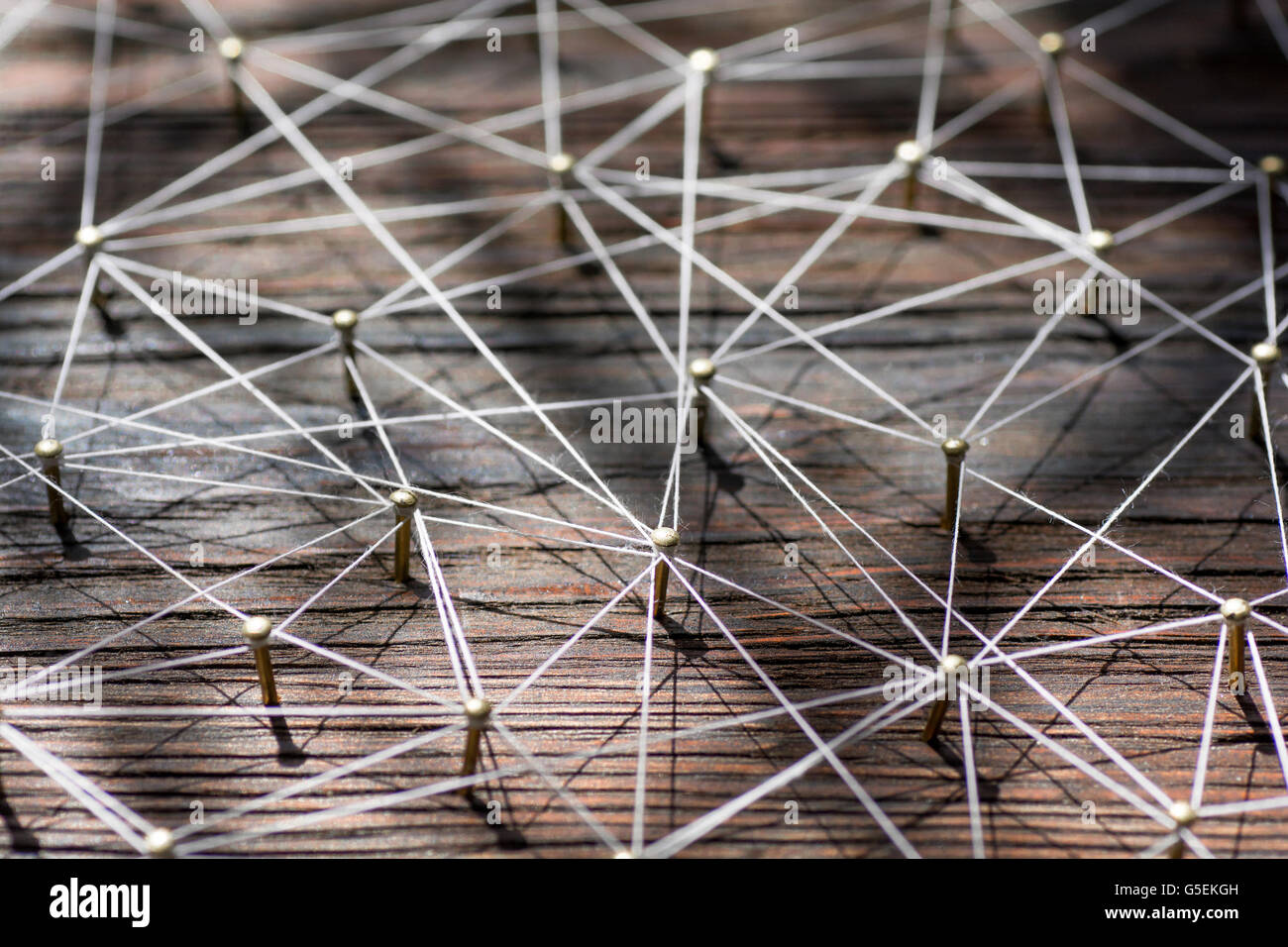 Linking entities. Network, networking, social media, internet communication abstract. A small  connected to  larger . Web of gold wires on rustic wood. Stock Photo