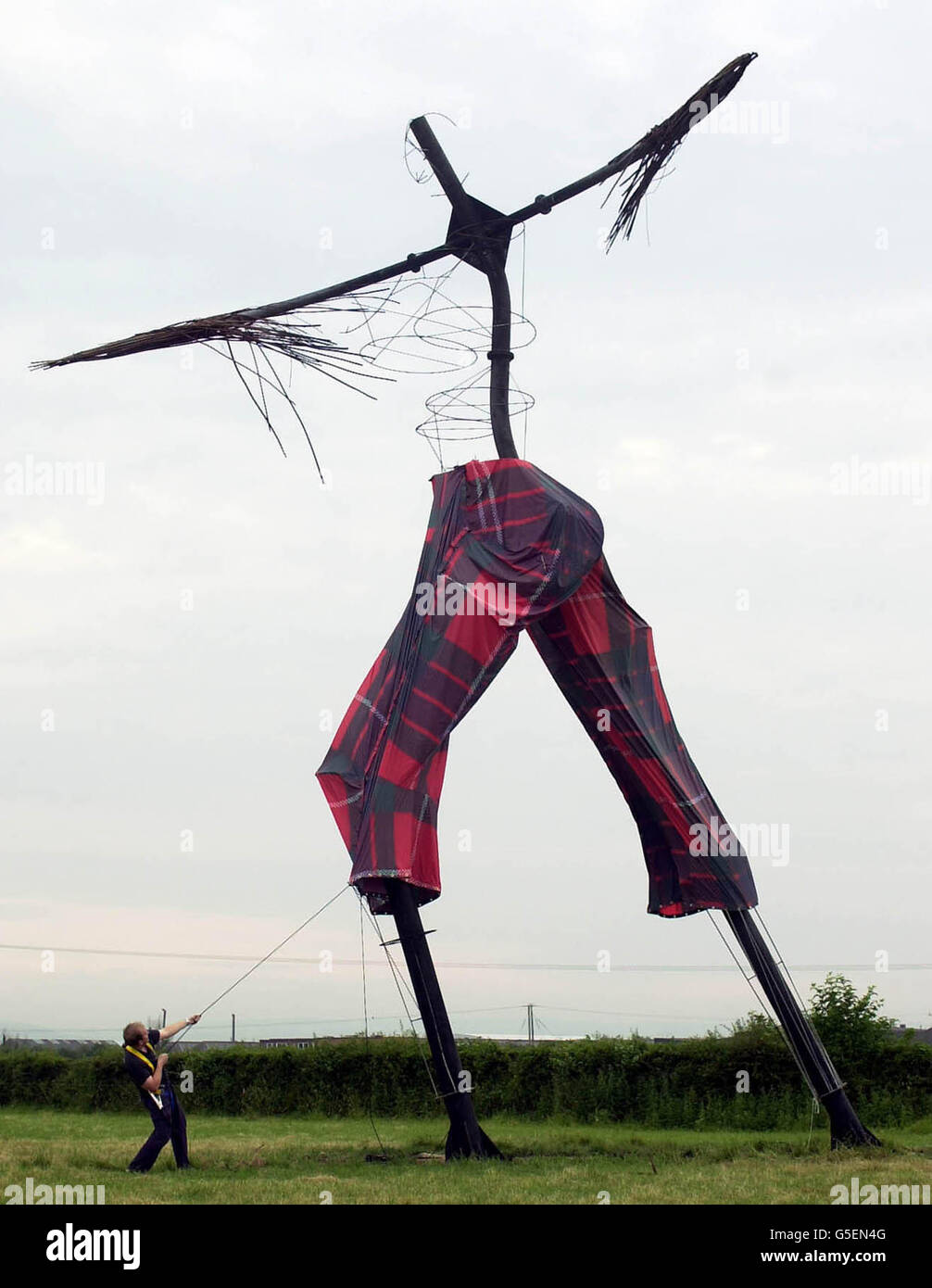 The skeleton of the giant sculpture 'Willow Man' gets a final adjustment to his tartan 'Wrong Trousers' for Wallace & Gromit's Wrong Trousers Day alongside the M5 motorway near Bridgwater, Somerset. * The trousers, made of 70 metres of red Fraser tartan print balloon fabric, have been made to measure by Cameron Balloons for the 12 metre high sculpture, which has an inside leg of about 6 metres. The event asks people across the South West to donate 1 to support the new Bristol Children's Hospital or to sponsor others to wear some unusual leg wear. Stock Photo