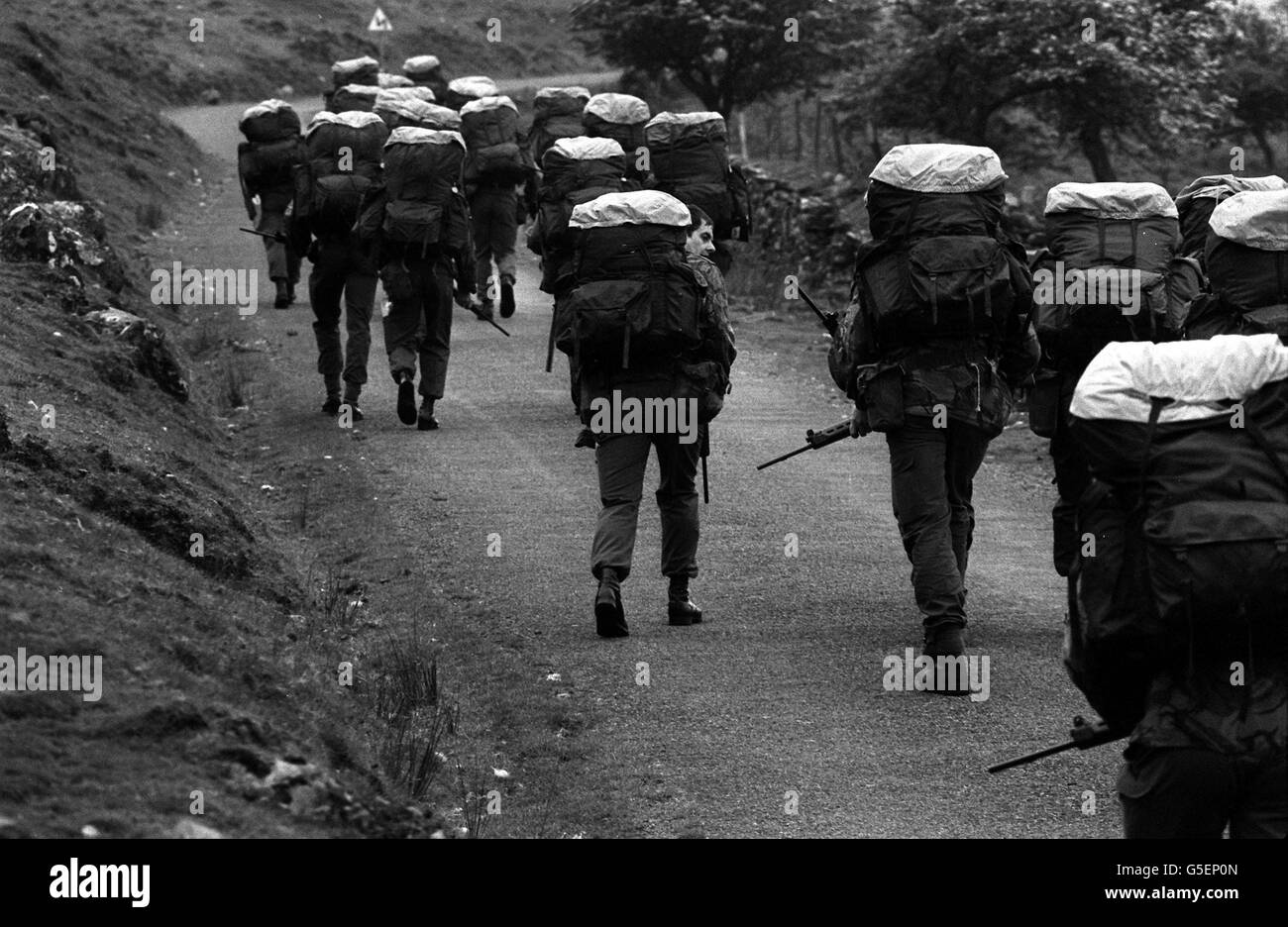 1981: SAS (Special Air Service) recruits with 45lb back packs and 10lb FN rifles having to walk to the top of a mountain peak before the official start of an endurance march across country because the track is too steep for an Army truck. A recruit who ate a 1lb chocolate bar, making his pack lighter, had to carry a 2lb rock instead. Stock Photo