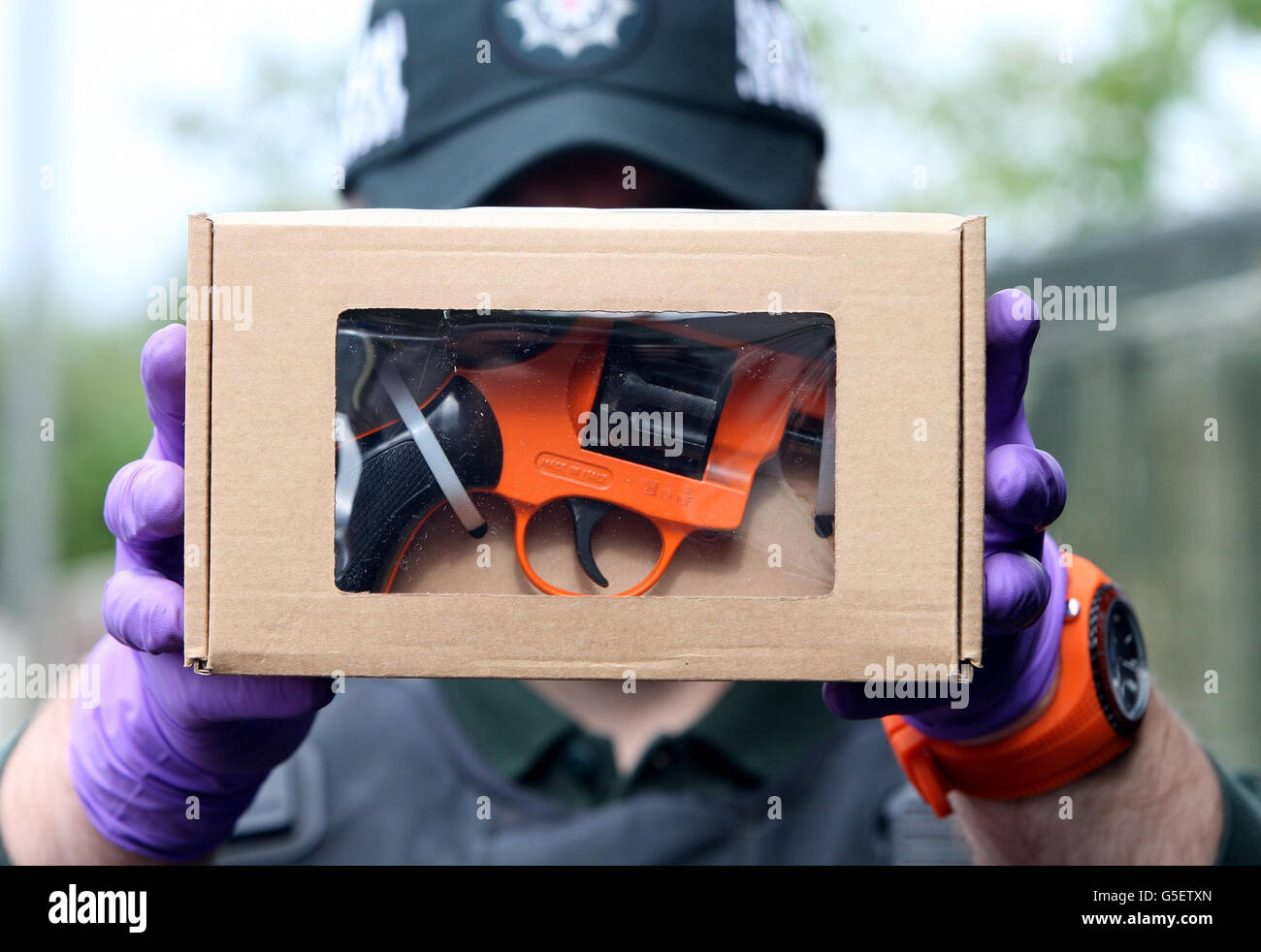 A Police Officer Displays A Firearm Discovered In A House During A