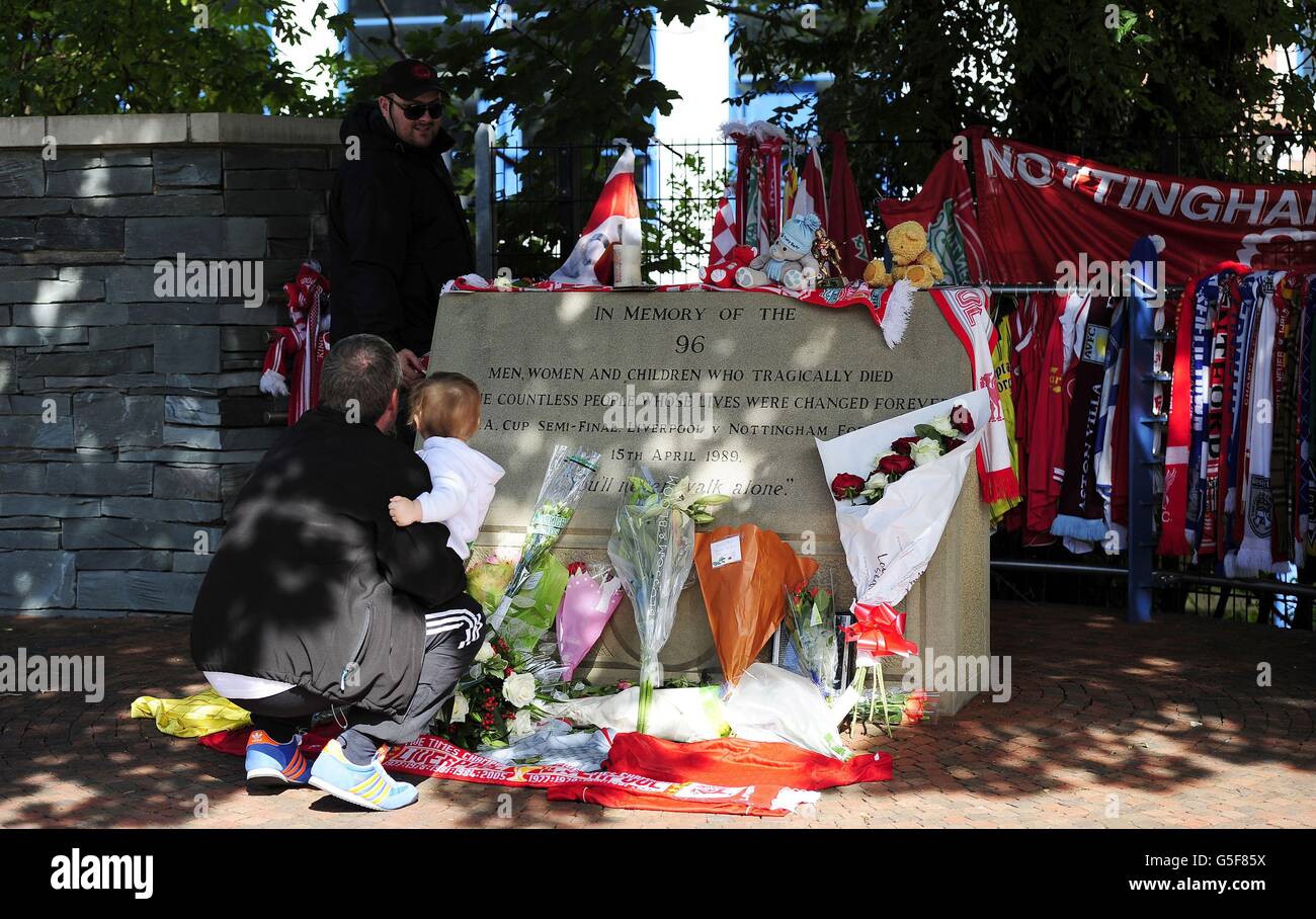 David Roberts, from Liverpool, (standing) outside Hillsborough Football Ground in Sheffield, while his father, also named David (left), holds Kyle Roberts, as the two Hillsborough survivors returned to the ground for the first time in 23 years to look at tributes left to the 96 people who died in the disaster. Stock Photo