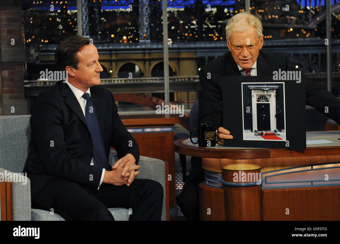 Prime Minister David Cameron (left) looks on as talk show host David Letterman, holds up a picture of Larry the cat sitting on red carpet outside the front door of 10 Downing Street, during the David Letterman Show in New York, after he addressed the United Nations General Assembly. Stock Photo