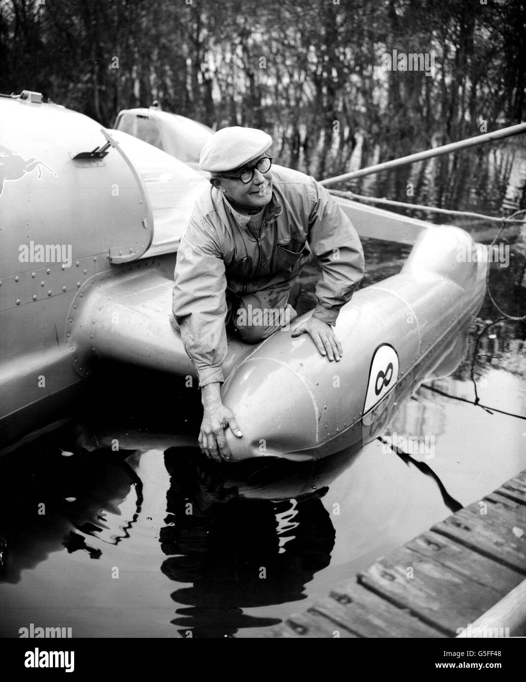 LEO VILLA 1957: Leo Villa, chief engineer to Donald Campbell, examines a damaged float of the jet-engined Bluebird II on Coniston Water in the Lake District. The float was damaged in the United States during Campbell's unsuccessful attempts to break his own water speed record. Stock Photo