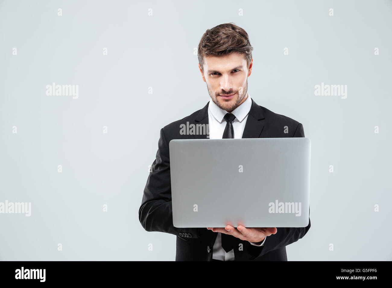 Confident young businessman in suit and tie using laptop over white ...
