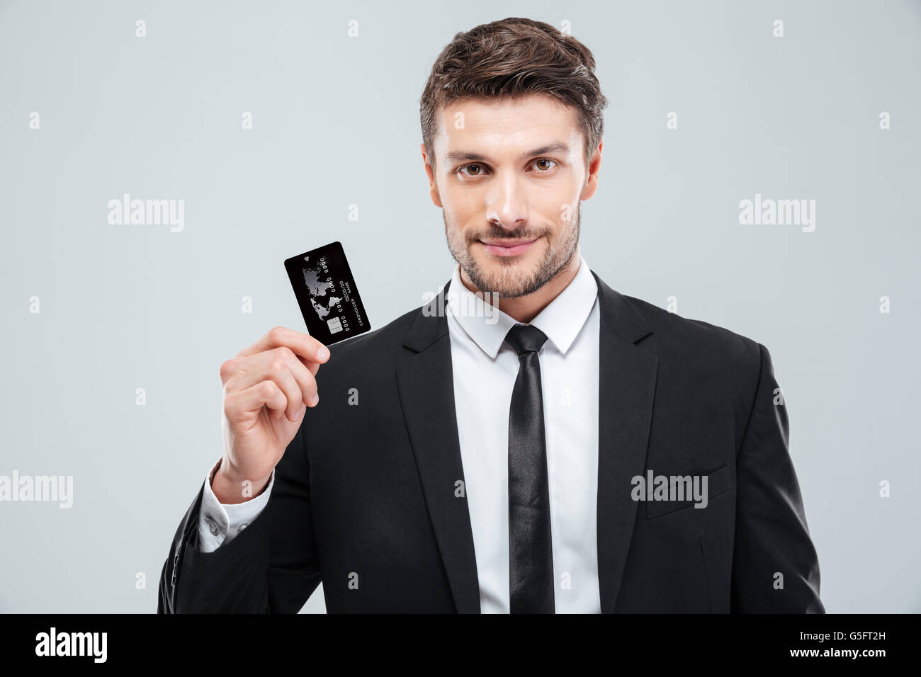 Portrait of handsome young businessman holding credit card over white ...