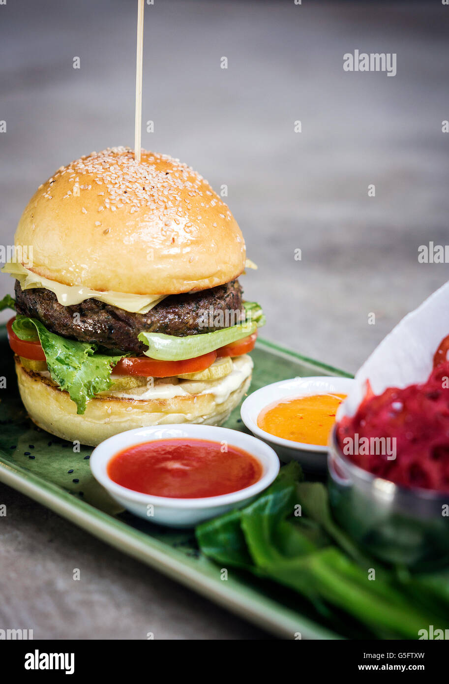 modern fusion beef burger set with lotus chips ketchup and spicy chlli sauces Stock Photo