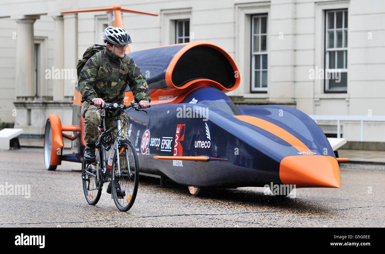 A soldier cycles past the Bloodhound Project jet engine and hybrid rocket motor powered car, at the Wellington barracks in central London, as Defence Minister Philip Dunne announced MoD involvement for the Bloodhound Project. Stock Photo