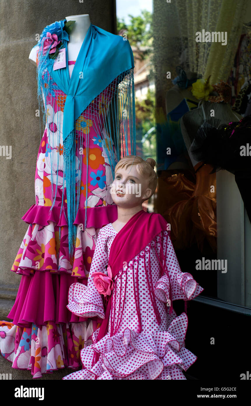 Two mannequins dressed in colourful flamenco outfits, pink and floral print dresses. One mannequin is headless the other a child Stock Photo