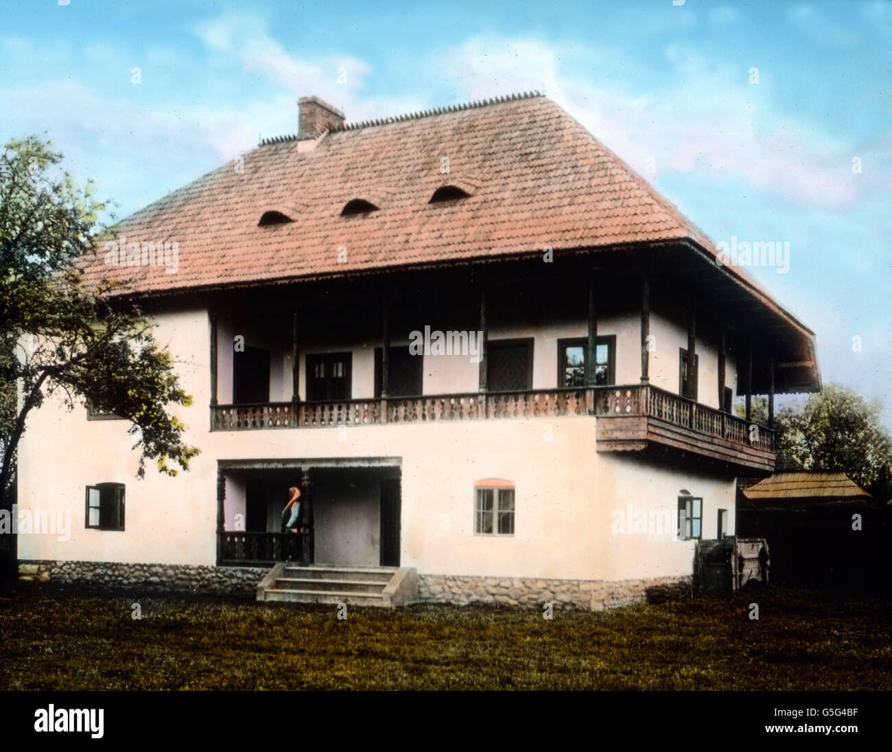 Haus eines wohlhabenden Bauern. The house of a wealthy farmer. Romania, Southeastern Europe, Balkan, history, historical, 1910s, 1920s, 20th century, archive, Carl Simon, hand coloured glass slide, house, architectire, modern, woman, standing, entrance, nice Stock Photo