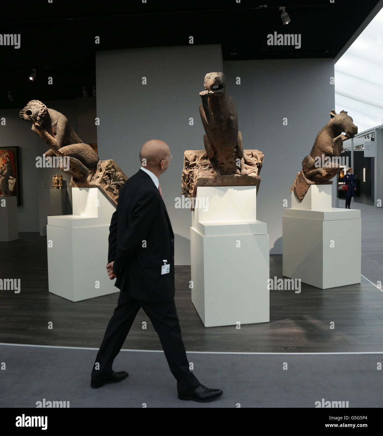 A visitor looks at Three Monumental Gargoyles, taken from the Oeuvre of the Notre-Dame Cathedral in Strasbourg, c.1275-1283, at the Frieze Masters art fair, at Regents Park in central London. Stock Photo
