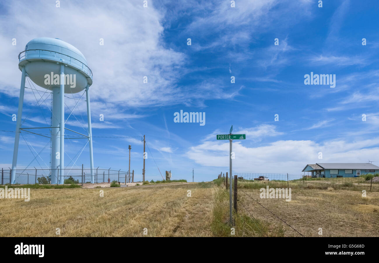 A small village in rural America in summer showing an elevated concrete water tank with view of a road sign and a wooden cabin. Stock Photo