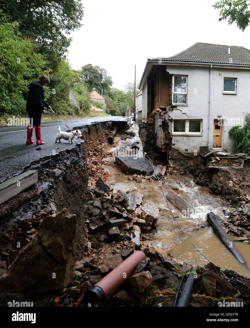 Autumn weather Oct 12. A women walking her dog views the damage caused to a house in Dura Den in Fife after heavy rainfall. Stock Photo