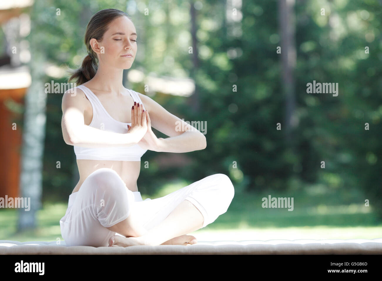 Young woman doing yoga lotus exercise outdoors Stock Photo