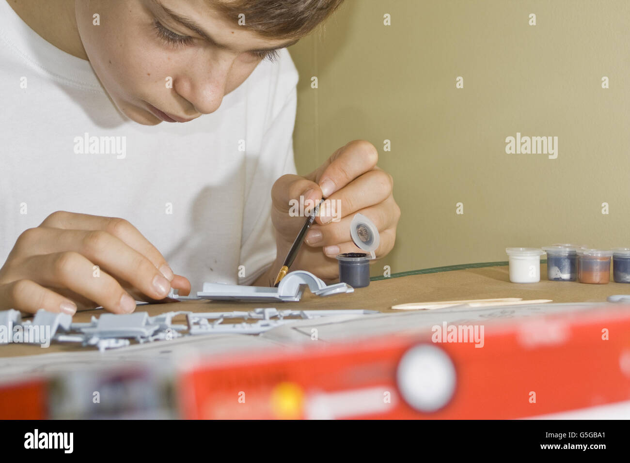 Teenager painting Airfix model parts. Stock Photo