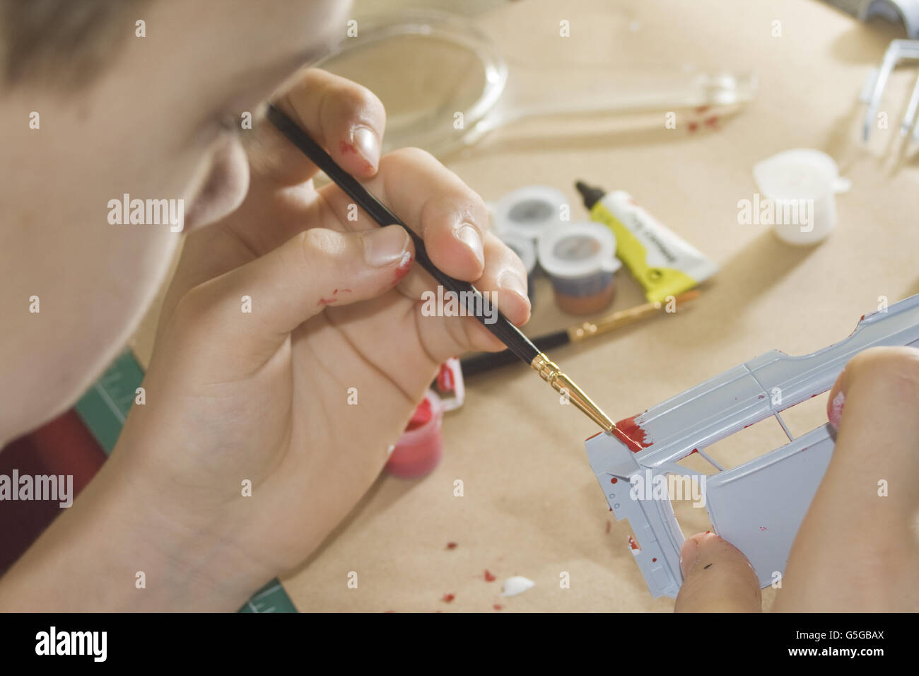 Teenager painting Airfix model parts. Stock Photo