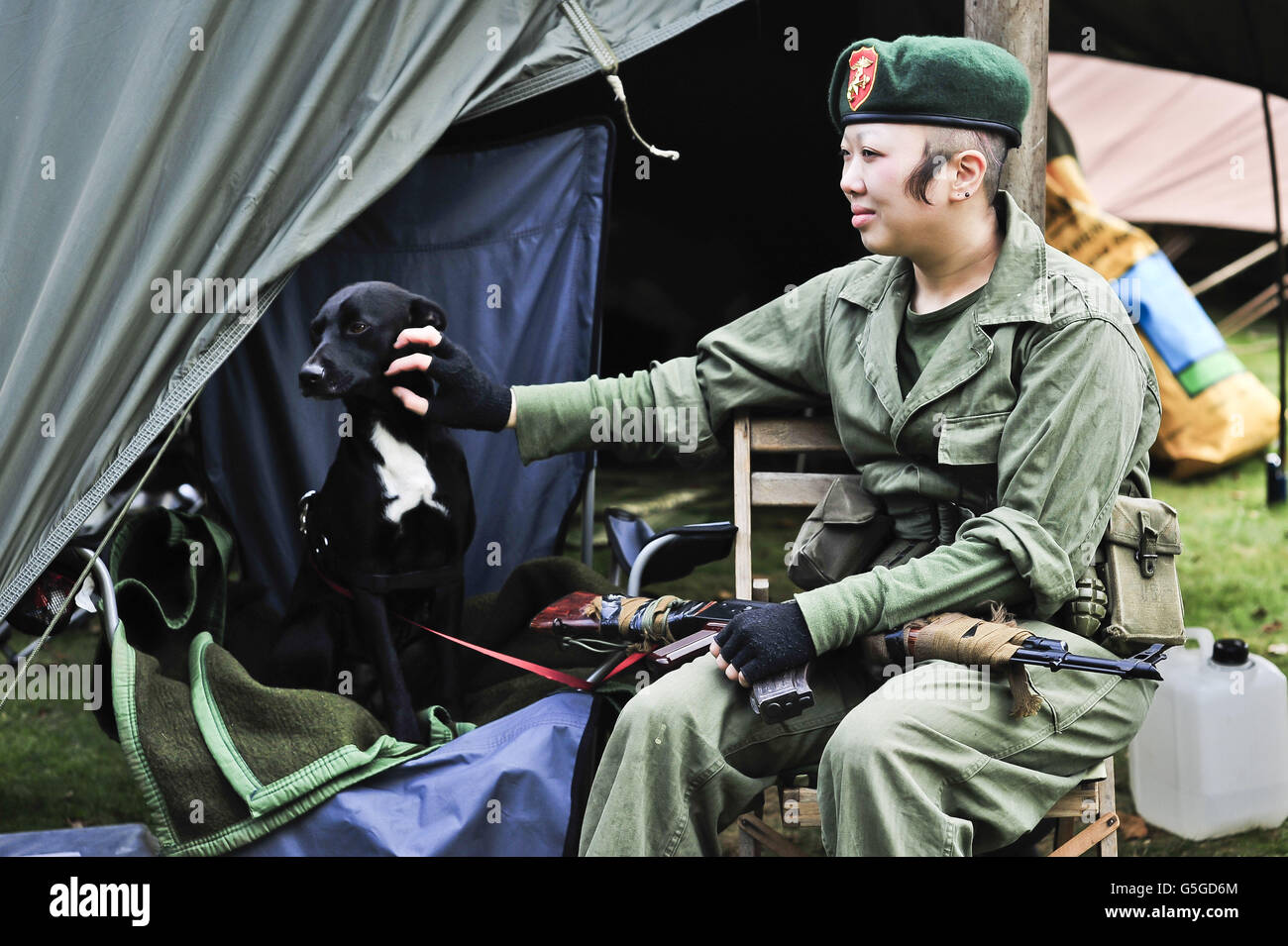STANDALONE Photo. A woman in period military uniform pats a dog while taking time out from a military display at the WWII Weekend at Castle Drogo in Devon. Stock Photo