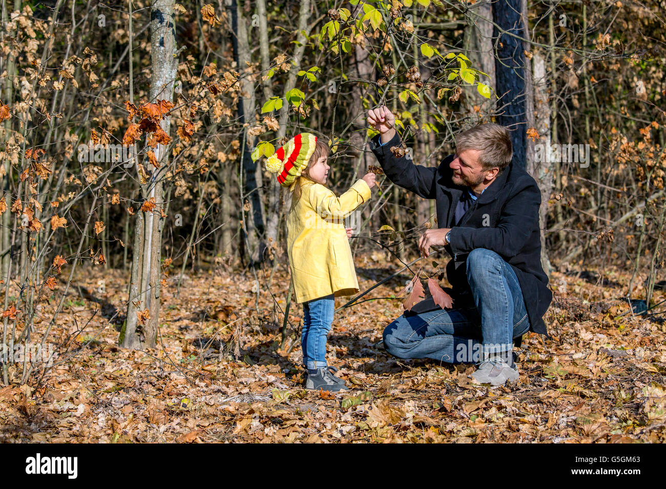 Father Playing with Little Baby Daughter in Autumnal Forest Stock Photo