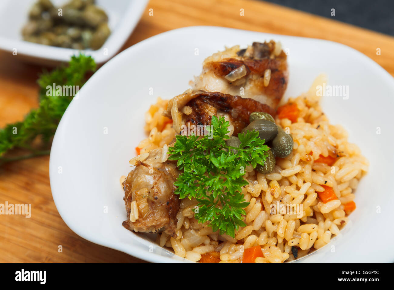 Pilaf with chicken, garnished with capers and parsley Stock Photo