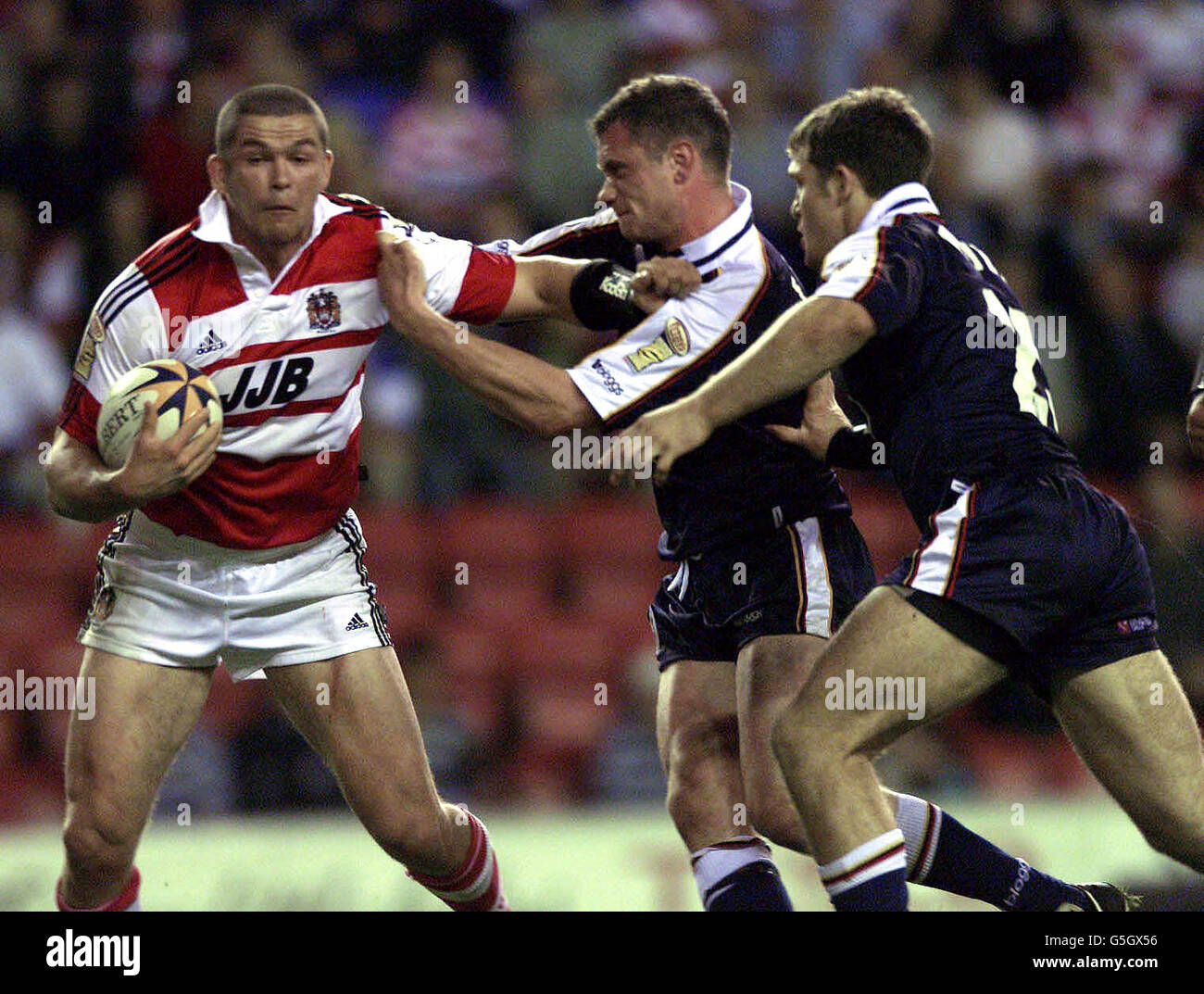 Wigan Warriors' Andrew Farrell trys to break Bradford Bulls' defensive line of Jamie Peacock and Stuart Fielden (far right) during the Tetley's Bitter Super League game at the JJB Stadium, Wigan. Stock Photo