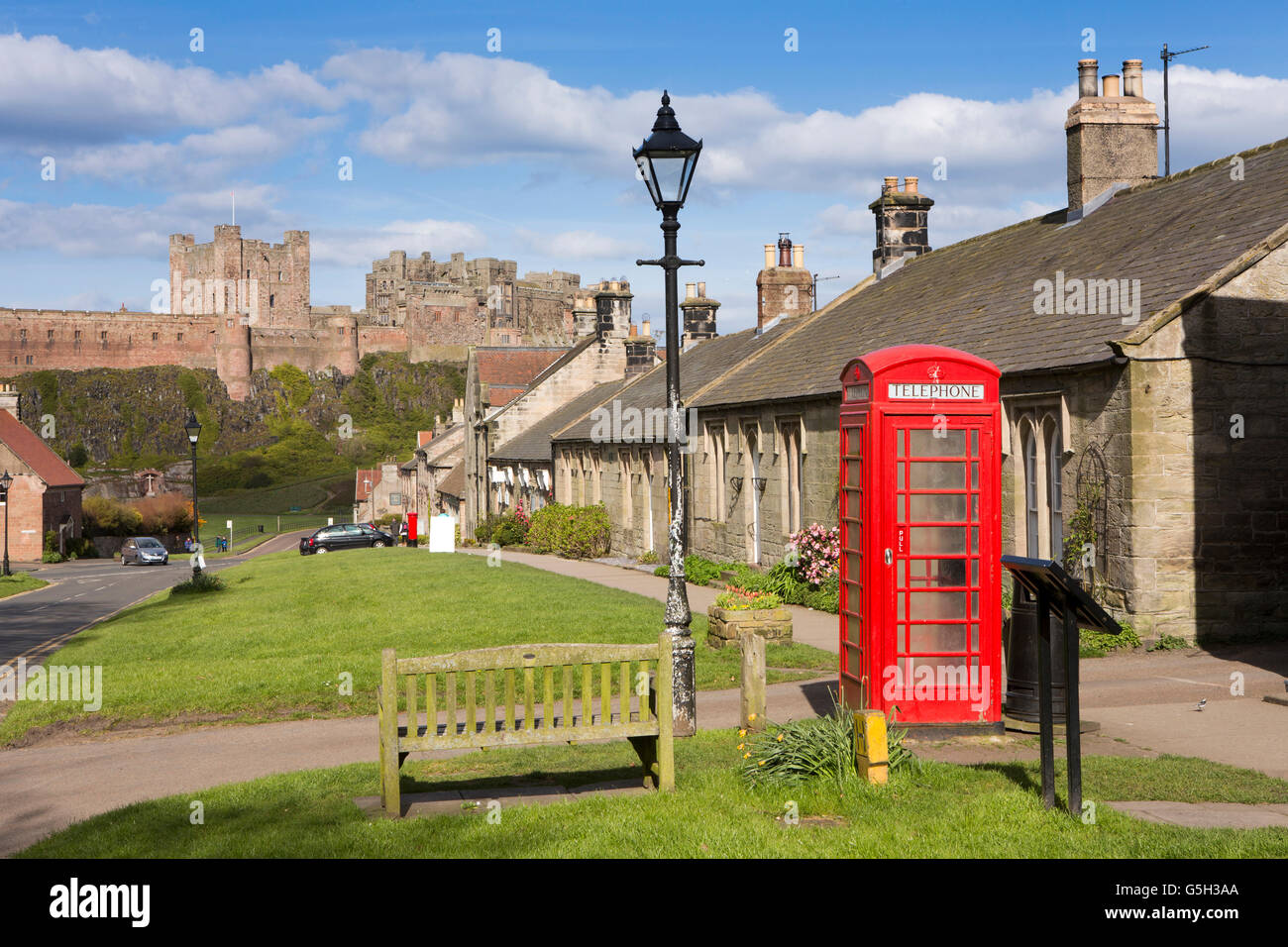 UK, England Northumberland, Bamburgh village, phone box on Front Street with castle beyond Stock Photo