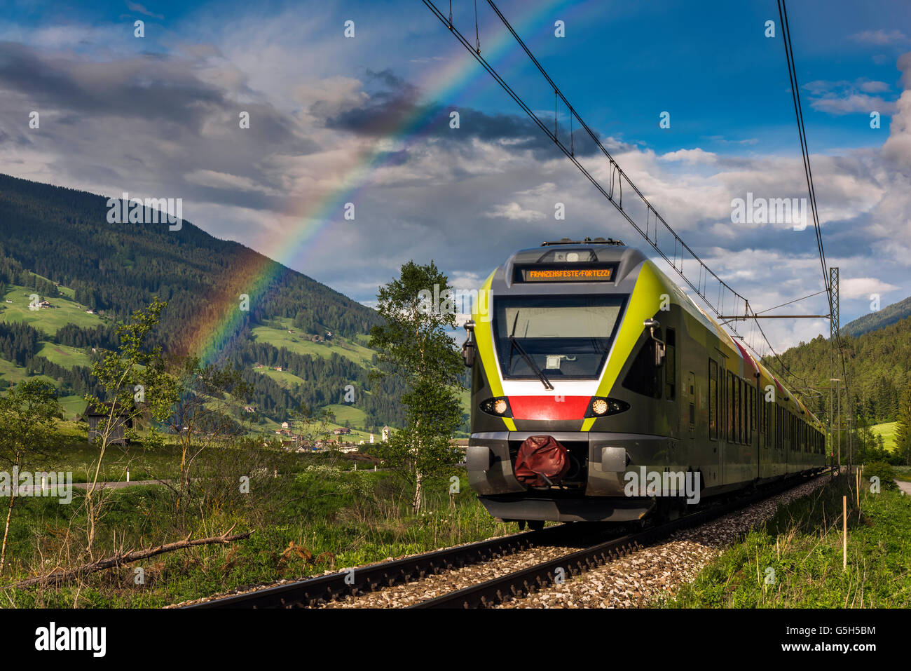 Mountain landscape with train and rainbow in Val Pusteria or Pustertal valley, South Tyrol, Italy Stock Photo