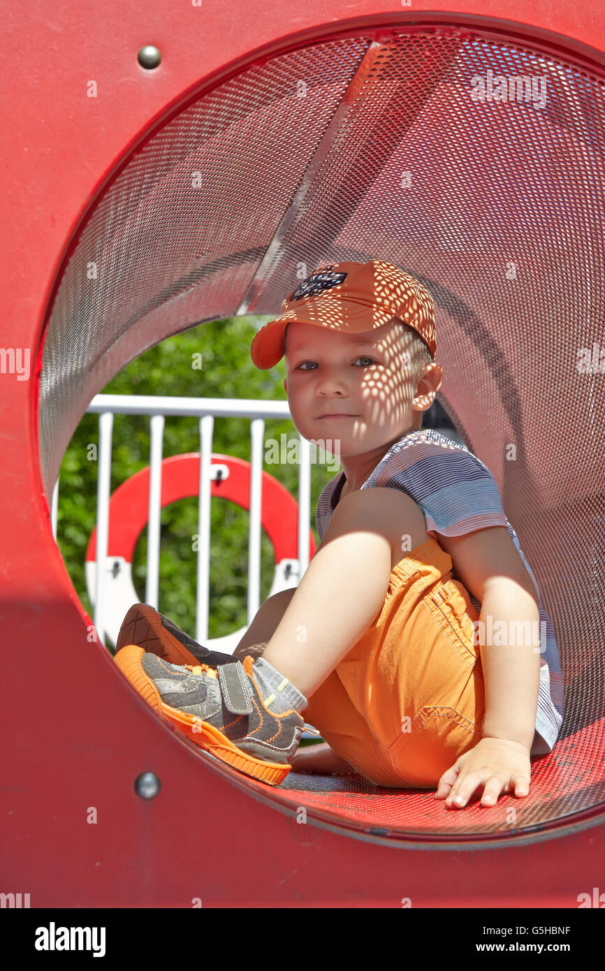 Cute boy playing in tunnel on playground Stock Photo