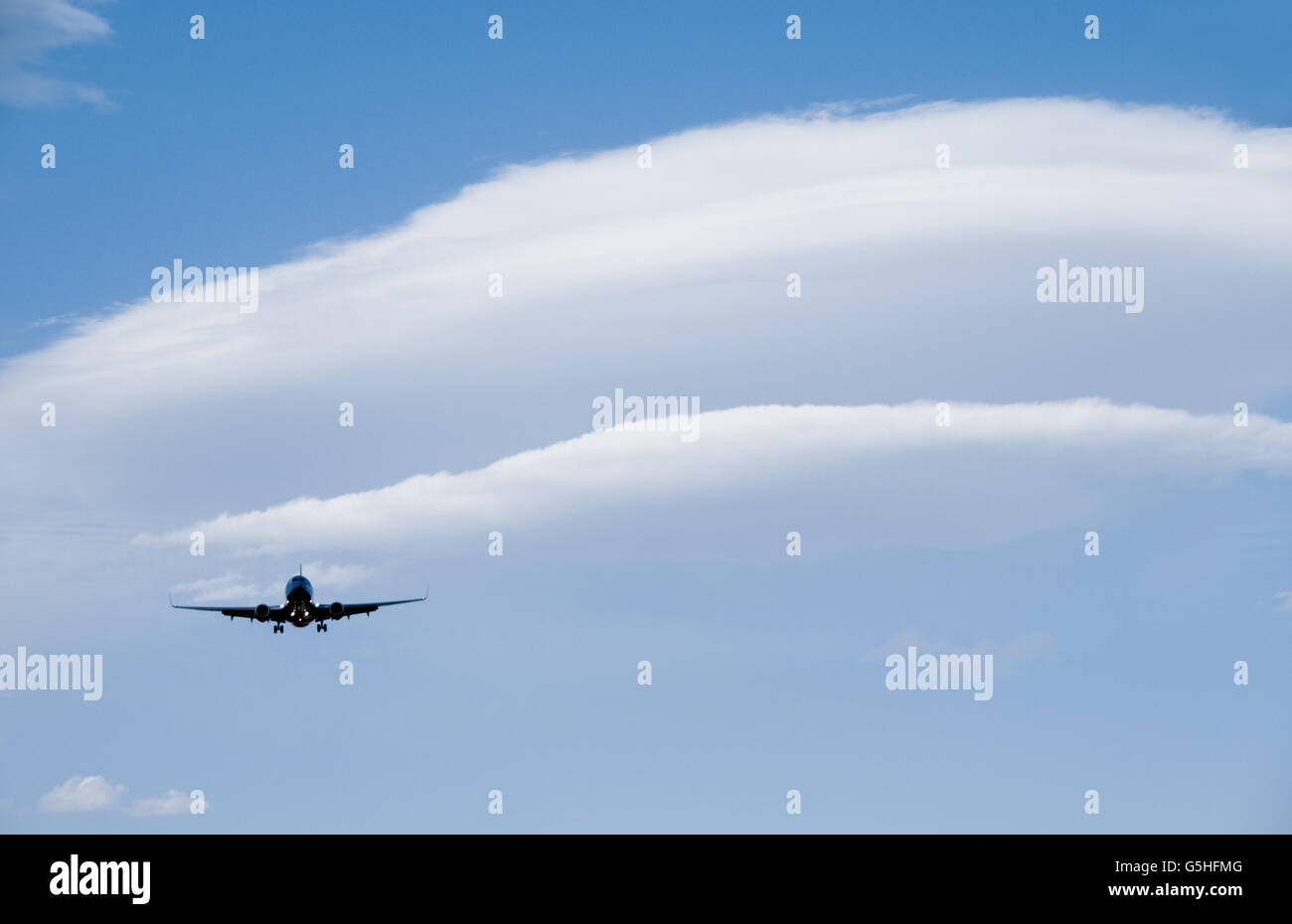 Boeing 737 jet airplane landing with Lenticular Clouds behind Stock Photo
