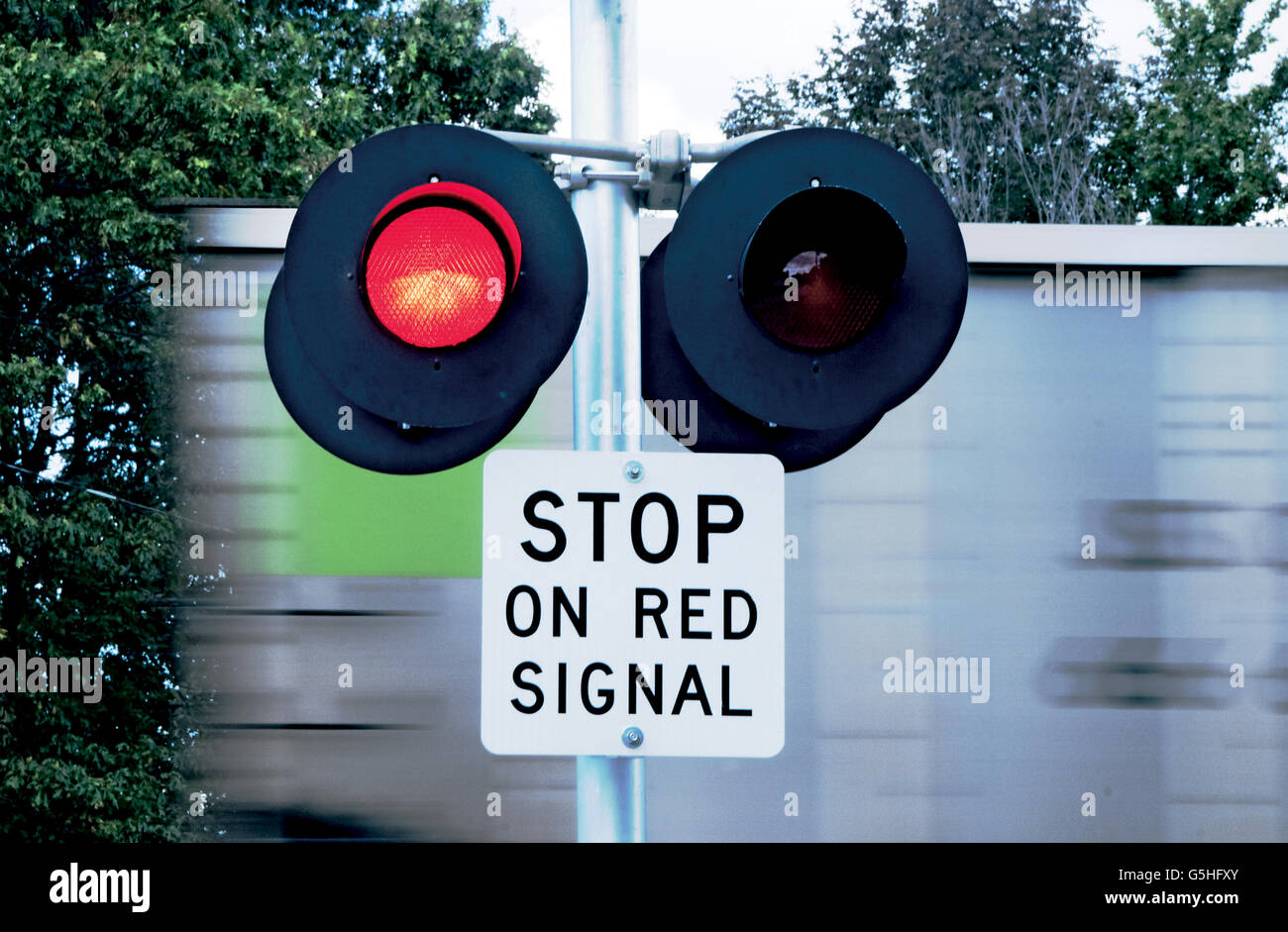 Train speeding past flashing warning lights at grade crossing Stock Photo