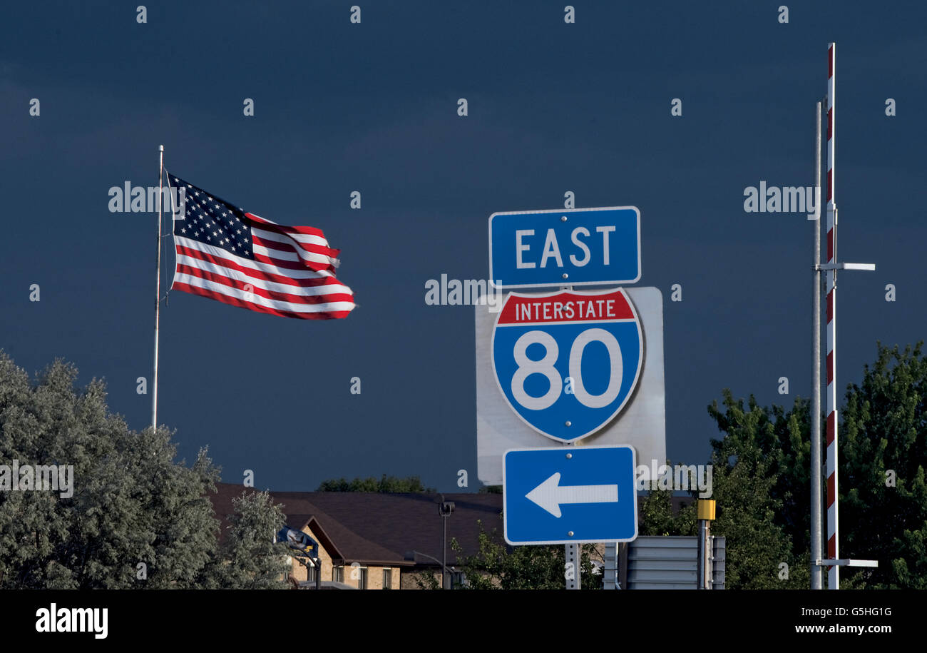 Onramp sign for Interstate 80 with U.S. flag and black sky from oncoming storm Stock Photo