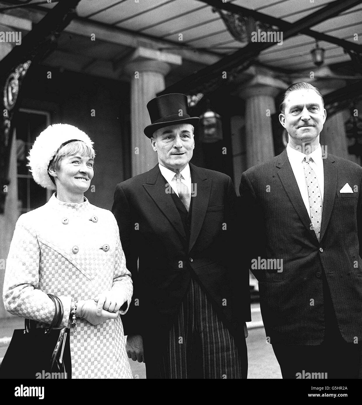 In morning dress and glossy top hat, Detective Chief Superintendent Thomas Butler, head of Scotland Yard's Flying Squad, leaves Buckingham Palace after receiving the insignia of Member of the Order of the British Empire (MBE) from the Queen at an investiture. He is accompanied by Detective Inspector 'Wilf' Pickles. Stock Photo