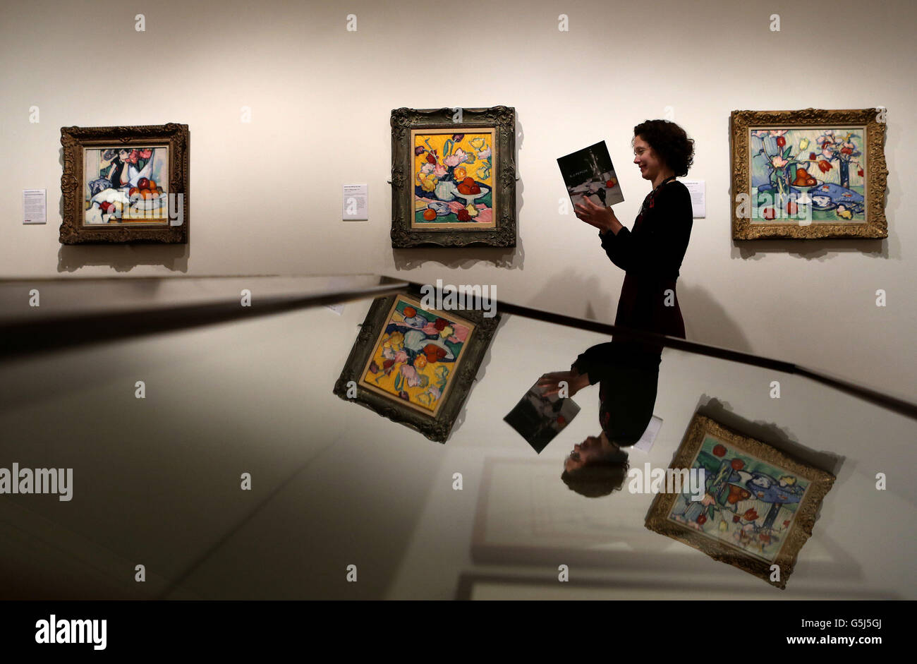 Curator Alice Strang reads a guide book next to paintings in the