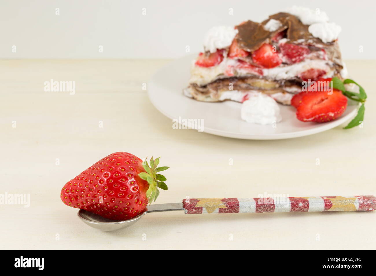 Strawberry in a spoon with slice of strawberry cake Stock Photo