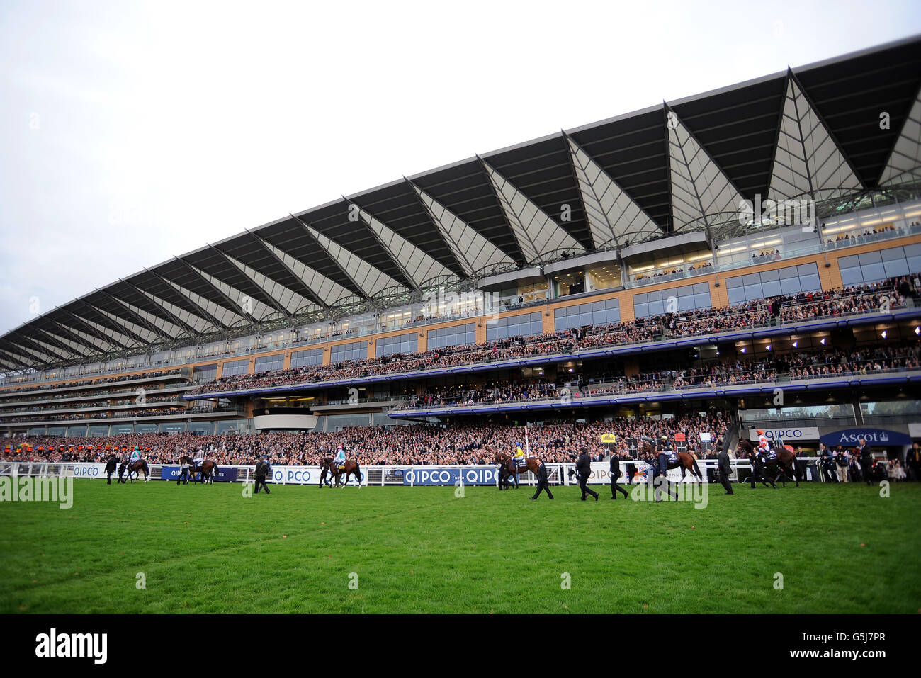 General view of the grandstand at Ascot racecourse as the horses parade in front of them to the start line Stock Photo
