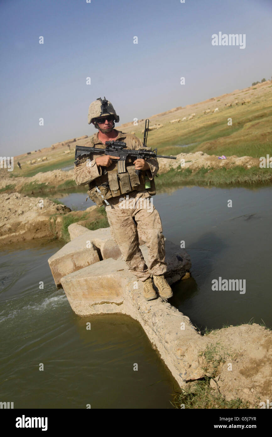 U.S. Marine crossing a bridge over a canal in Helmand province, Afghanistan. Stock Photo