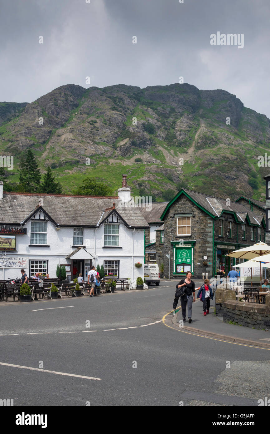 The Black Bull Hotel and Village Store with Fells Coniston  Cumbria England UK with dark rain clouds Stock Photo