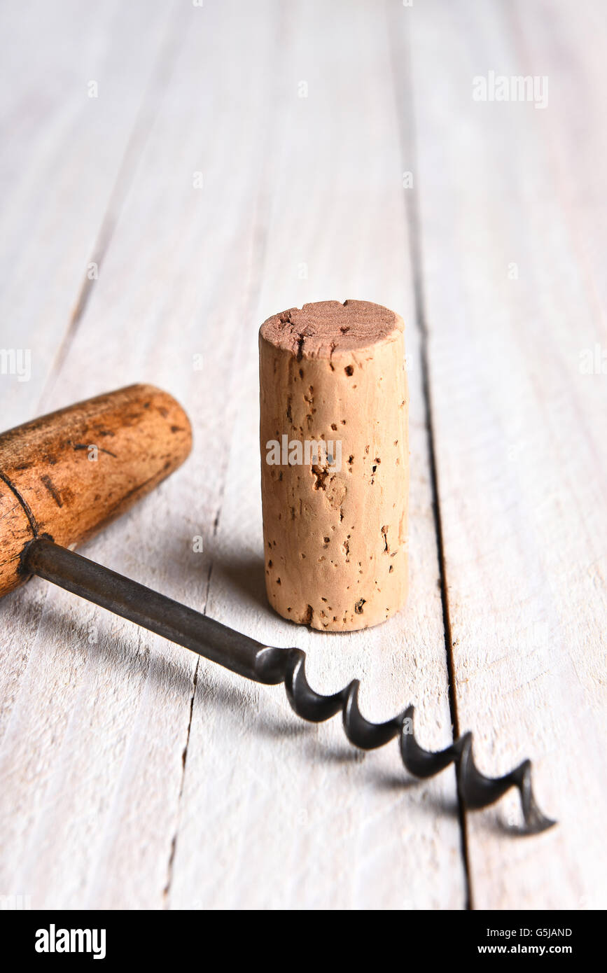 Still life closeup of a cork and corkscrew on a white wood table. Vertical format with copy space. Stock Photo