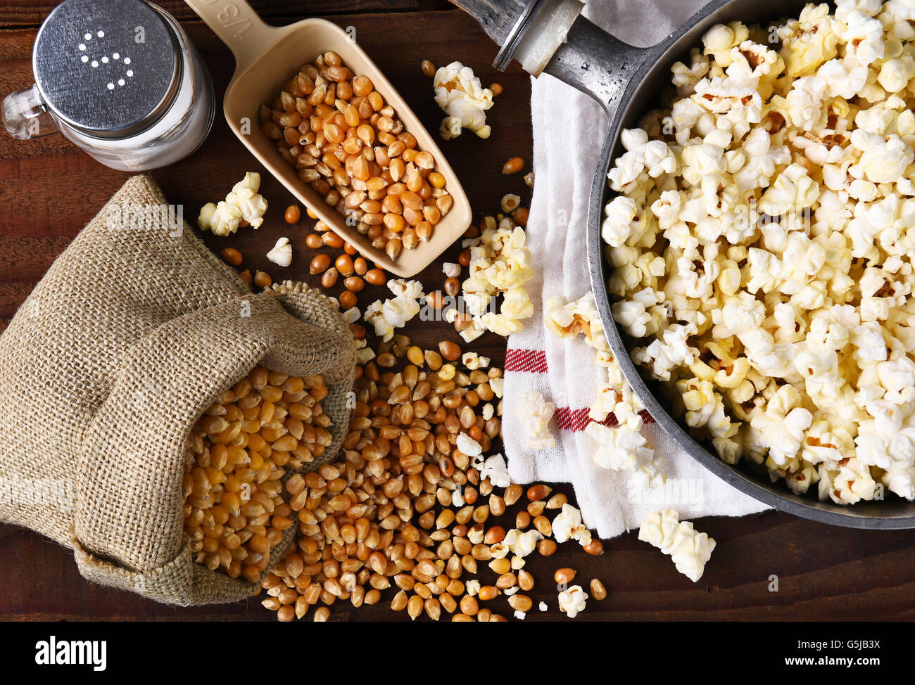 Top view of a pot full of freshly popped popcorn with salt and unpopped kernels on the side. Stock Photo