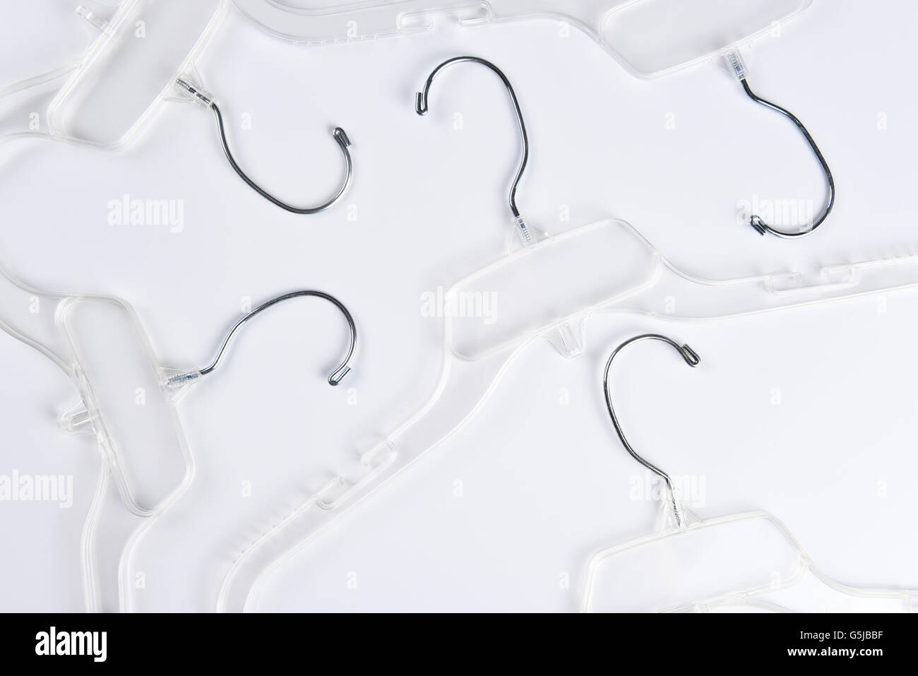 High angle view of a group of clear plastic clothes hangers on a white background. Stock Photo