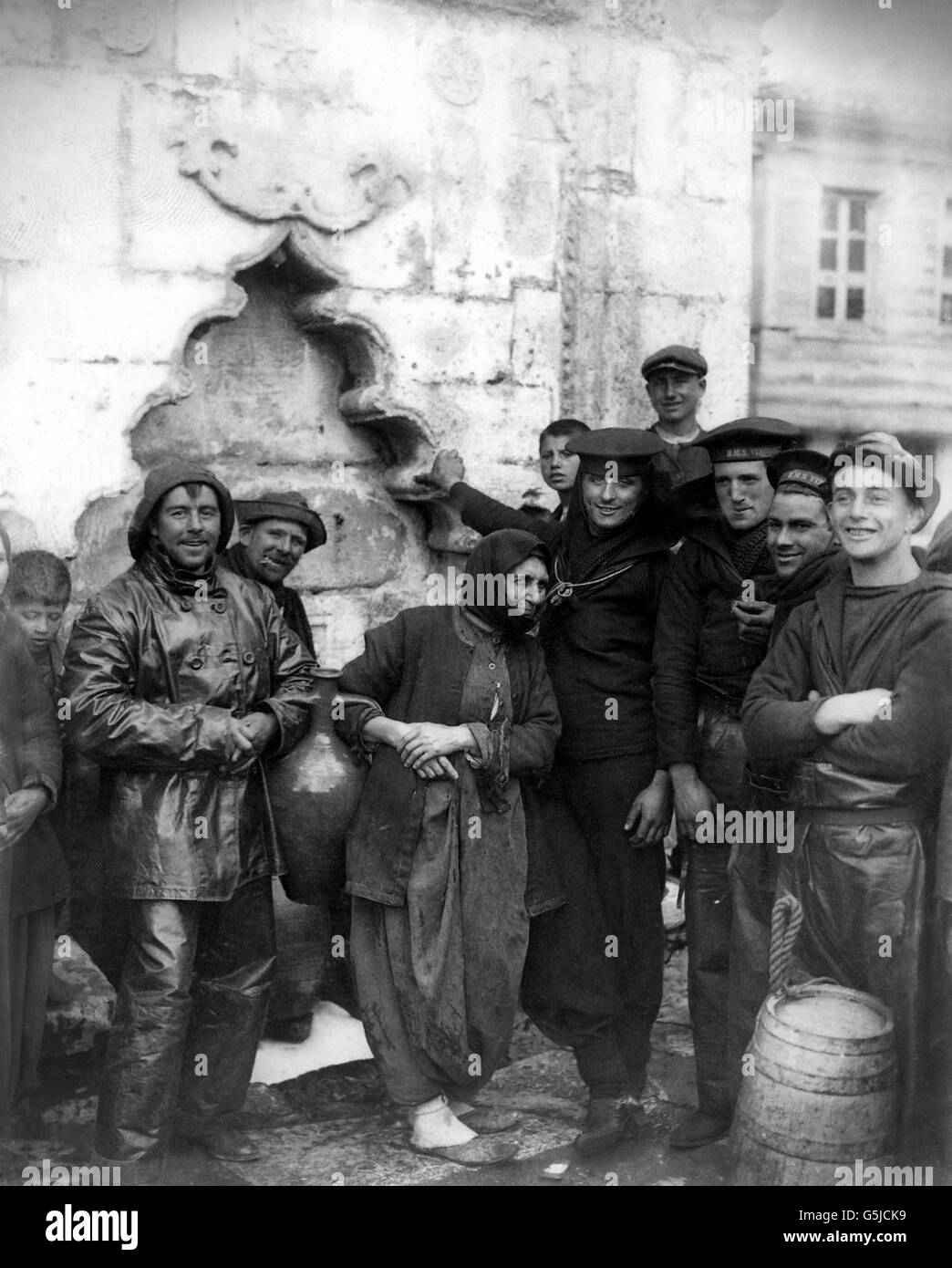 Sailors help a Turkish woman draw water from a well in the Dardanelles. Stock Photo